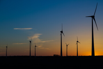 viele Windräder bei Sonnenuntergang stehen auf einem Feld und produzieren Strom	