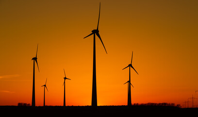 viele Windräder bei Sonnenuntergang stehen auf einem Feld und produzieren Strom	