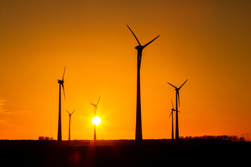 viele Windräder bei Sonnenuntergang stehen auf einem Feld und produzieren Strom	