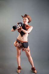 young brunette lady in cowboy costume holds professional photo camera in hands