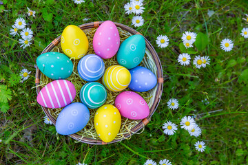 viele bunte Ostereier in einem Korb auf der Wiese	