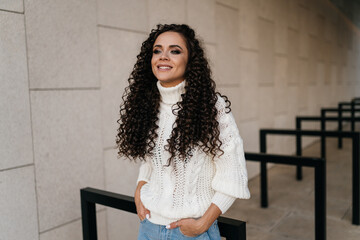 Fototapeta premium In the light tunnel stands curly brunette with a charming smile. High quality photo