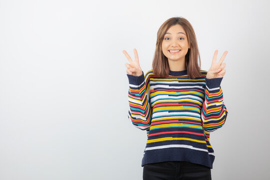 Picture of a positive cute girl model standing and showing victory sign