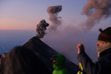 Fire volcano erupting at sunrise - volcano in Guatemala - tourists watching the natural spectacle
