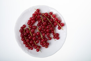 Fresh raw red currant berries on white plate