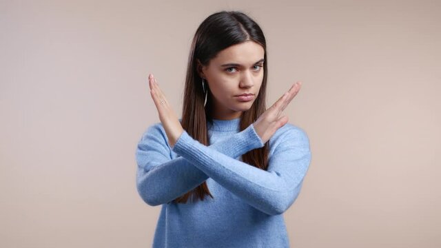 Cute girl disapproving with no crossing hands sign make basta, negation, enough gesture. Denying, Rejecting, Disagree, Portrait of pretty girl on white background