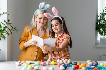 Mother and daughter together at home celebration concept sitting reading greeting card