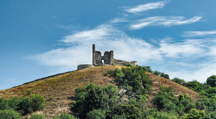 Obraz premium DEVIN, SLOVAKIA - JUNE 10, 2020: Ruins of Devin Castle on confluence of Danube an Morava rivers near Bratislava. View from river, against blue sky.