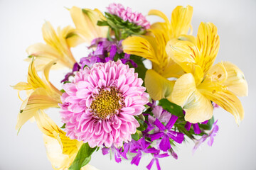 Small pink and yellow flower arrangement of asters and alstromeria in a vase. Colorful spring flower arrangement isolated on white.