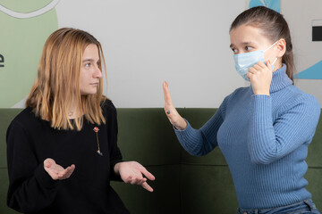 Young blonde girl asking something wrong with her friedn
