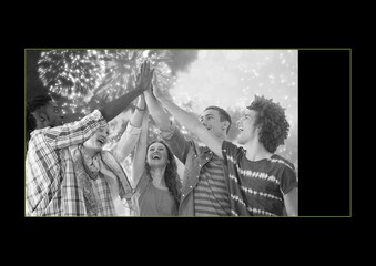 Black and white photo of group of friends high fiving in yellow frame on black background