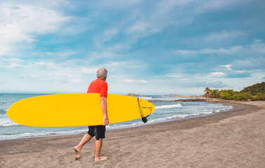 Fototapeta na wymiar old man holding a surfboard