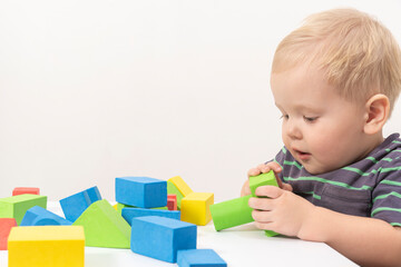 Little boy plays cubes on a light background. high quality