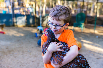 Boy holding pet chicken in coop