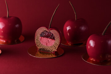 cherry-shaped chocolate mousse. dessert with biscuit base, icing and fruit filling on a red background