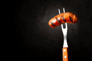 Grilled barbecue sausages on dark background. - obrazy, fototapety, plakaty