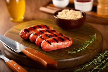 Grilled barbecue sausages on wooden background.