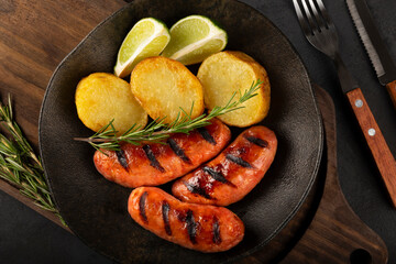 Grilled barbecue sausages on dark background.