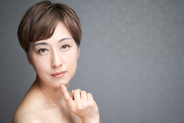 Obraz na płótnie Canvas カメラ目線で顎に指をあてる中年の日本人女性