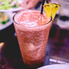 Strawberry natural fruit juice with a slide of pineapple in a big glass with straws