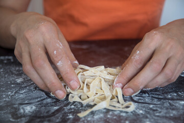 Preparing homemade fettuccine on a wooden maza. traditional cutting concept of Italian cuisine, cutting raw dough into tagliatelle on copy space