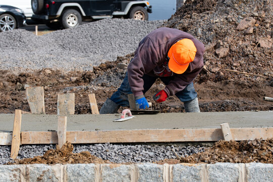 construction worker leveling concrete pavement outdoors