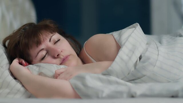 woman cannot sleep because of the noise, covered her ear with a pillow at night