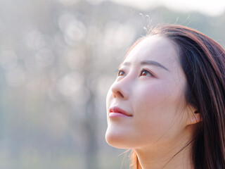 Close up portrait of beautiful young Chinese woman, looking away with smiling expression, head shot side view with left copy space.