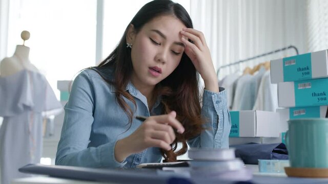 Young attractive asia female business owner thoughtful serious doubtful feel stress worry with financial problem in SME crisis small business challenges impact from covid coronavirus at home office.