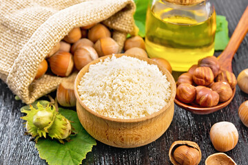 Flour in bowl with nuts on black wooden board