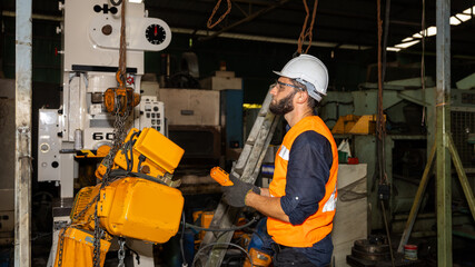 Male mechanical engineer or worker with hardhat and safety uniform checks the operation system in a factory