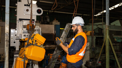 Male mechanical engineer or worker with hardhat and safety uniform checks the operation system in a factory