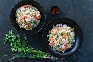 Asian fried rice with shrimp on the black dish in Thai. Prepared in wok. Top view.