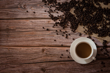 Top view of coffee in white cup and coffee beans on the wooden table with copy space
