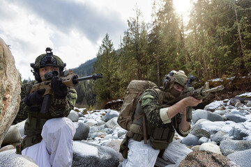 Army Man wearing Tactical Uniform and holding Machine gun in the Outdoor Rain Forest. Winter Warfare. Taken in British Columbia, Canada.