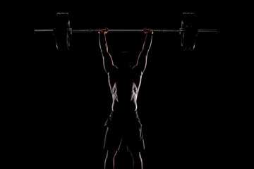 Athlete lifting barbell. Silhouette of a muscular man