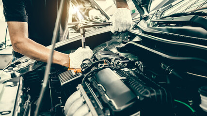 Close-up hands of auto mechanic are using the wrench to repair and maintenance auto engine is...
