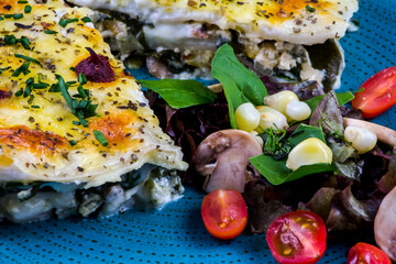 Vegetarian lasagne topped with toasted pine nuts and melting cheeses. Salad