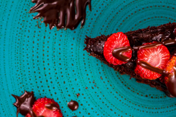 Naklejka premium chocolate cake with strawberries in turquoise dish