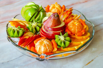 Pear, apples, oranges, tangerines, bananas and kiwi on a glass plate. Fresh mix of fruits.