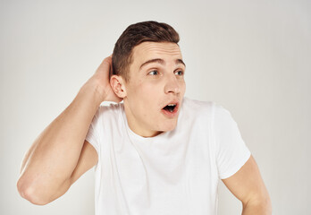 Nice guy in a white T-shirt on a light background cropped view portrait close-up