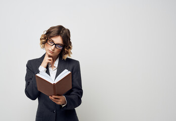 Business woman with a book in her hands on a light background Puzzled look Copy Space