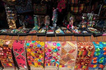 Obraz premium Colorful table runners, jewelry and purses on display at market stand 