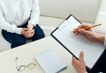 White sheet of paper a man writes information and a woman at a table indoors