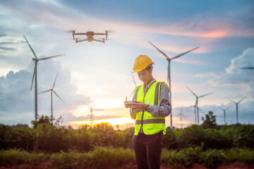 asian  male engineer flying drone surveying and checking wind turbines from the high angle view of...
