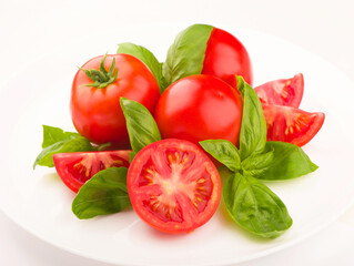 Tomatoes and basil leaves isolated on white close up. Vegetables