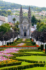 Urban landscape of Guimaraes in Portugal with its symmetrical gardens of green plants and colorful flowers, cathedral and historical buildings in the background.