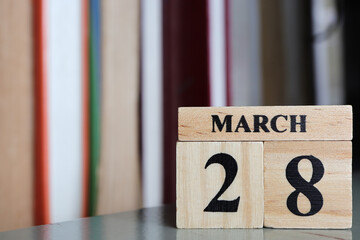 Day 28 of March month, Wooden calendar with date on the book shelf.