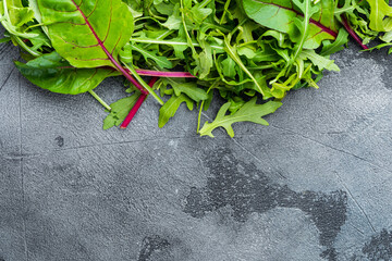 Obraz na płótnie Canvas Healthy salad, leaves mix salad Arugula, Chard, on gray stone background, top view flat lay, with copy space for text