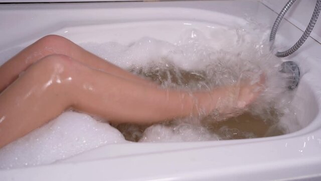 Close-up of female feet in a bath, she slowly moves them.
